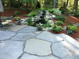 Landscaping beside patio with a water feature